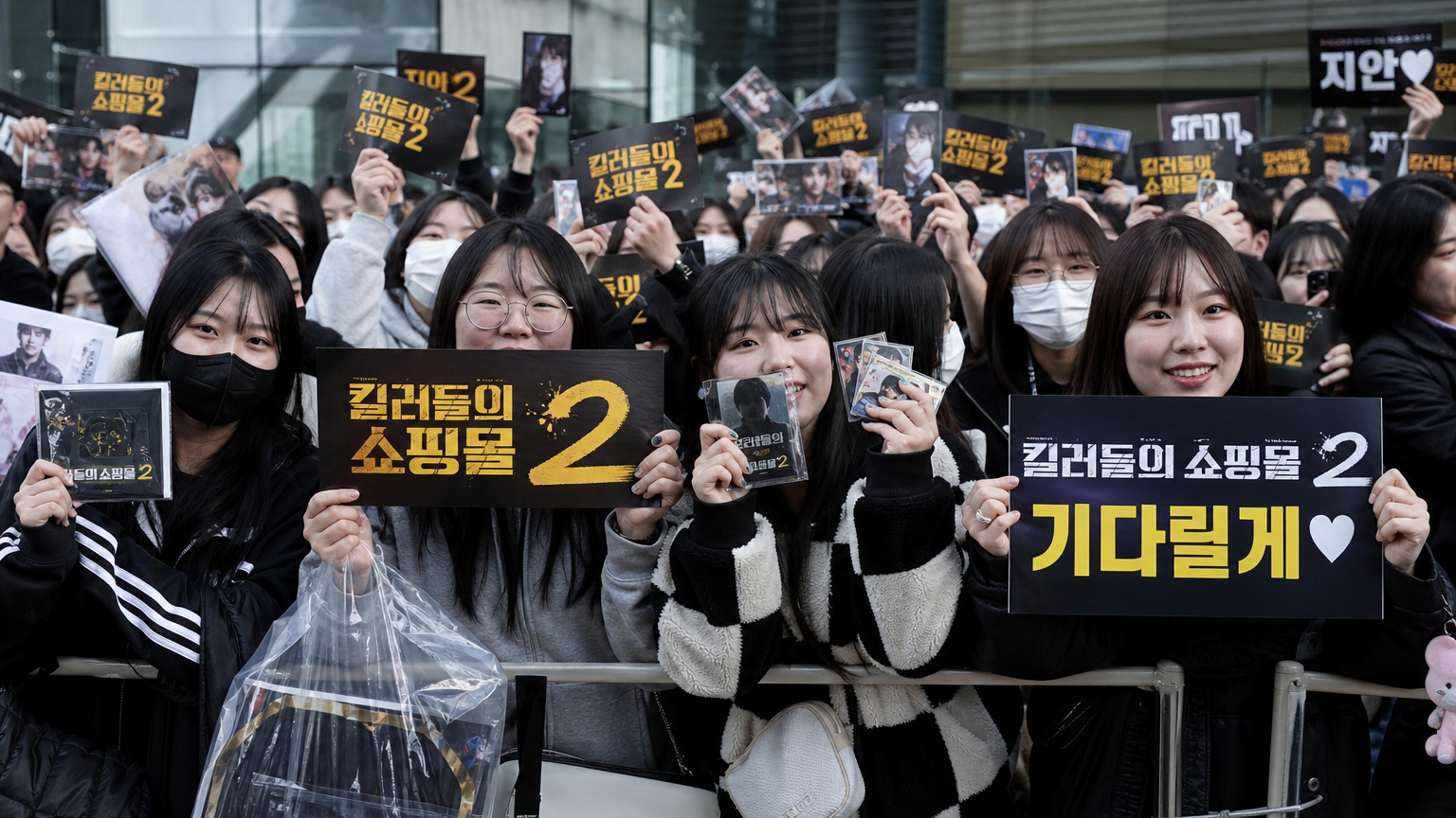 팬들이 '킬러들의 쇼핑몰 시즌2' 관련 상품과 표지를 들고 있는 모습