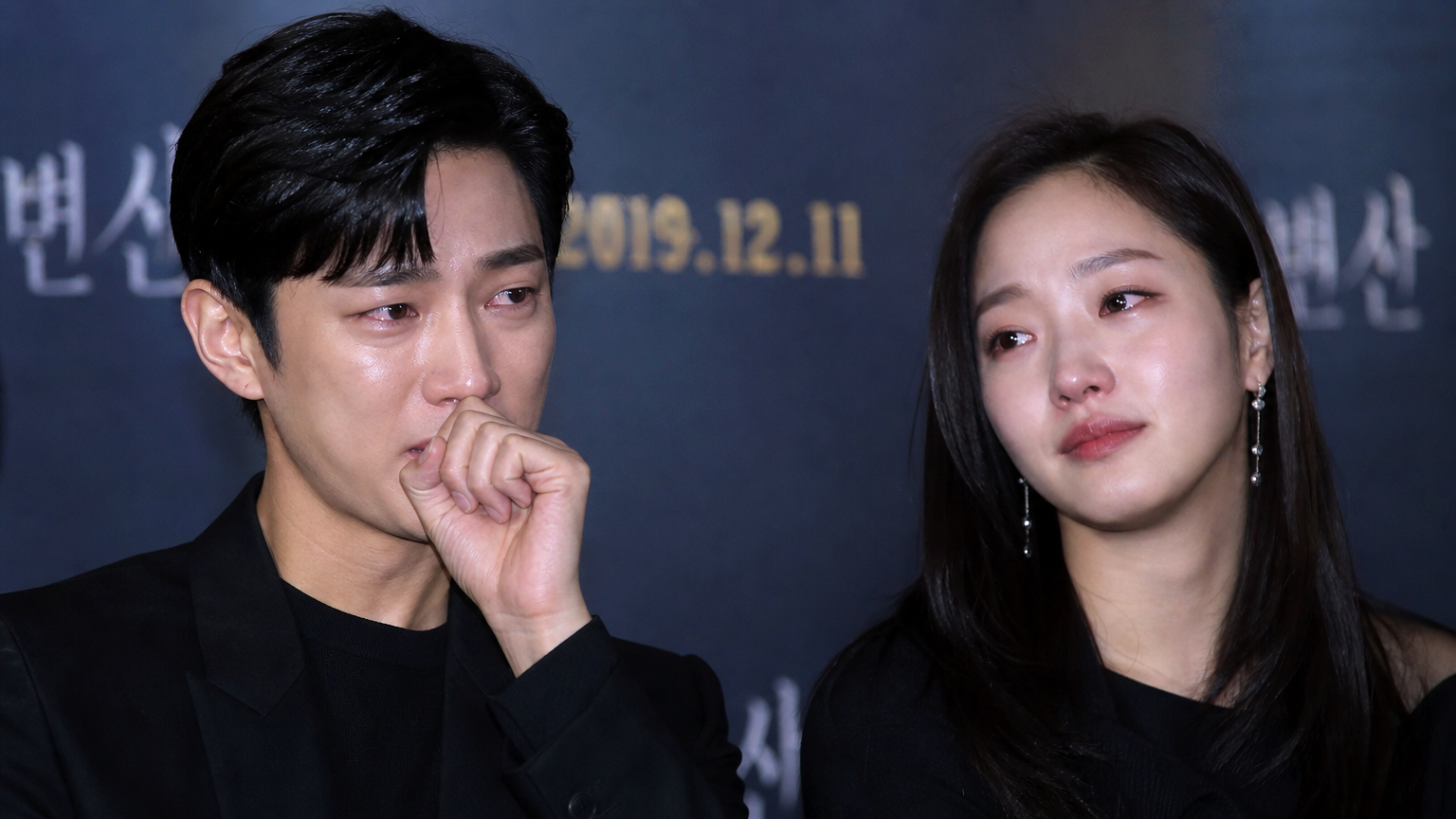 두 명의 한국 배우가 감동적인 영상 메시지를 보고 눈물을 흘리며 진심 어린 표정을 짓는 장면